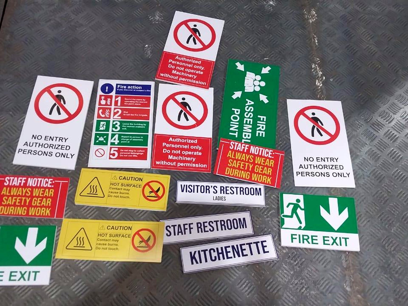 A set of printed safety and wayfinding signs including fire exit and no entry plates