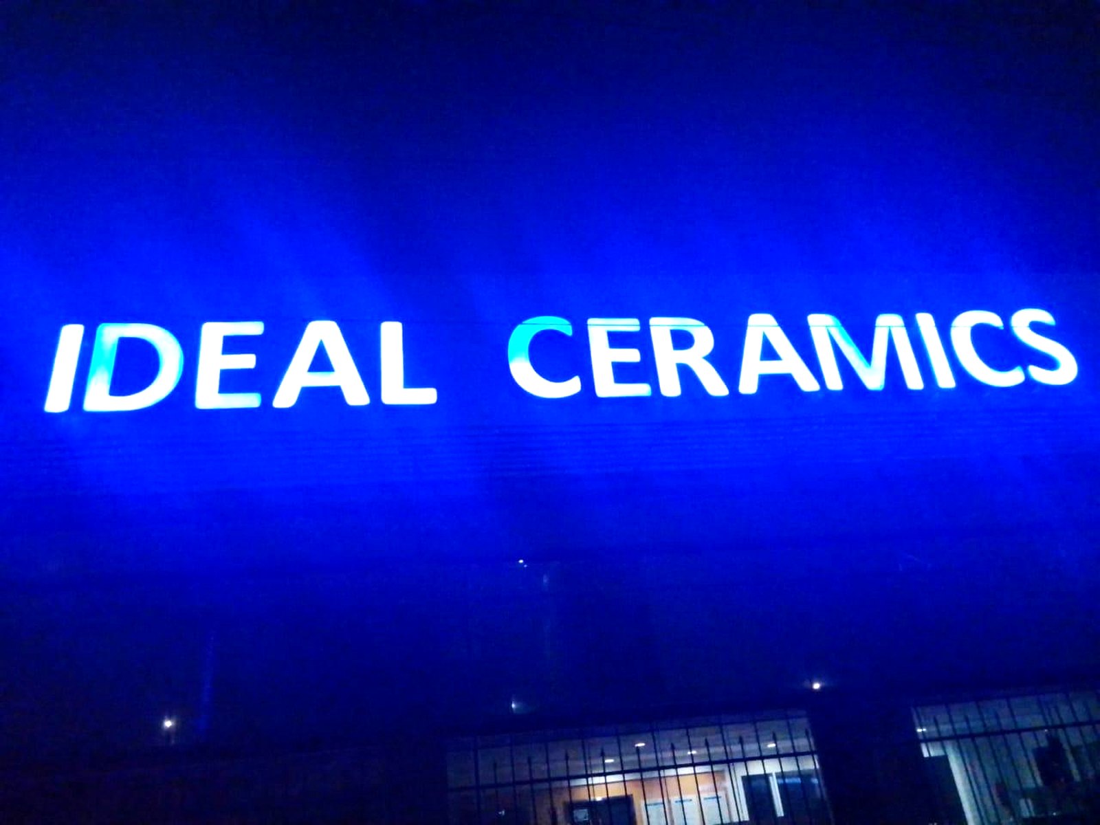 Ideal Ceramics illuminated storefront lettering glowing blue at night