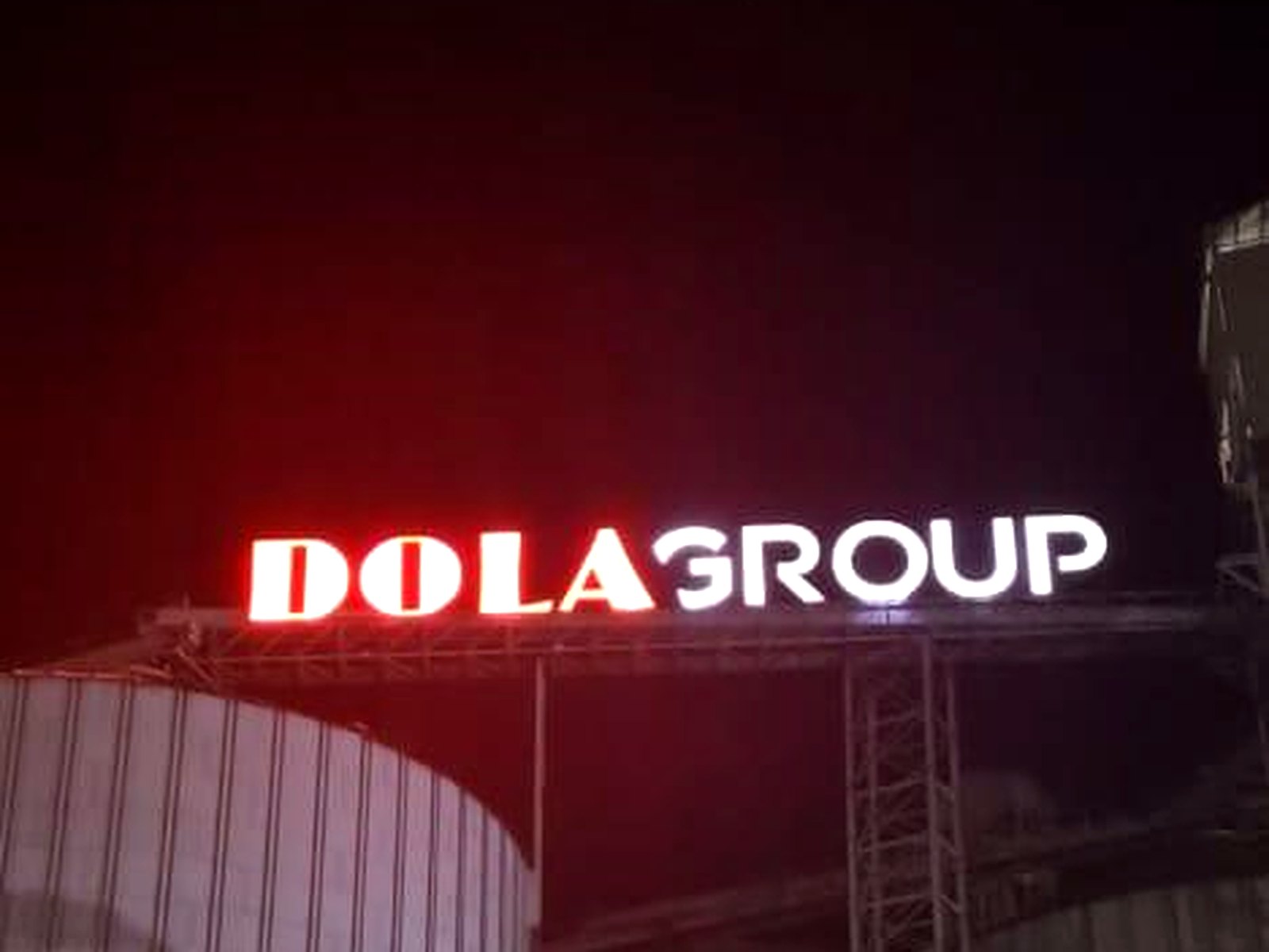 Illuminated Dola Group lettering above grain silos at night
